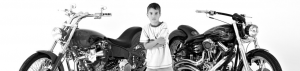 A boy standing in front of two motorcycles.